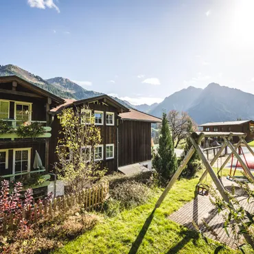 Kurzurlaub im Alphotel Alpenhäuser mit Blumenbalkonen und Spielplatz in sonniger Berglandschaft